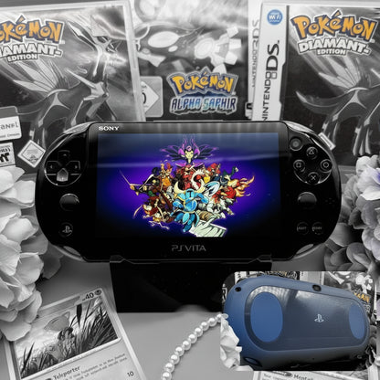 PlayStation Vita displaying a Pokémon game with Pokémon trading cards and gaming cases in the background. Black PS Vita modded console with Pokemon games - custom firmware PlayStation portable UK