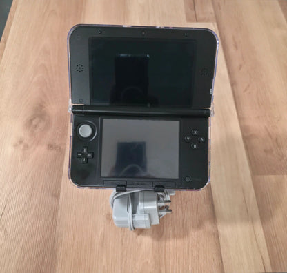 Black handheld gaming console with a strap on a wooden surface Modified Nintendo 3DS XL with custom firmware, Luma3DS, homebrew apps, emulators, customizable themes, and enhanced performance features.