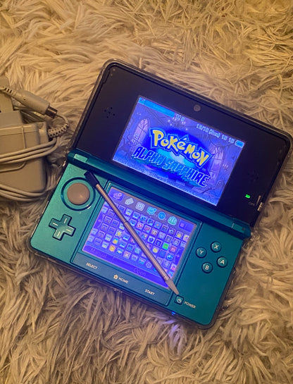 Nintendo 3DS gaming console with a game displayed on a textured surface Red Nintendo 3DS with a game displayed on a desk with computer equipment. Handheld 128gb 256gb custom firmware emulators anemone h shop modded 3ds 3dsxl new2dsxl 2ds N3DSXL new gaming retro handheld 