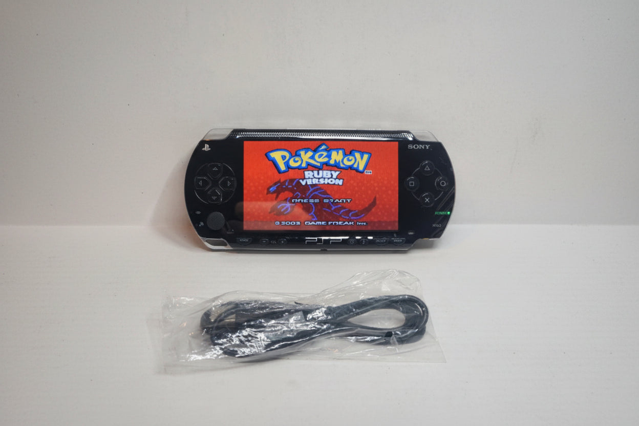 PlayStation Portable (PSP) with 'Pokémon Ruby Version' on screen and charging cable on a white background Sony PSP modded 128GB SD custom firmware pre-installed Pokemon emulators retro games UK handheld modding service