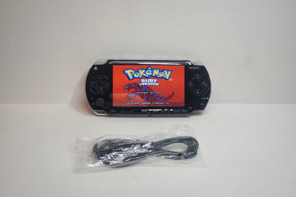 PlayStation Portable (PSP) with 'Pokémon Ruby Version' on screen and charging cable on a white background Sony PSP modded 128GB SD custom firmware pre-installed Pokemon emulators retro games UK handheld modding service