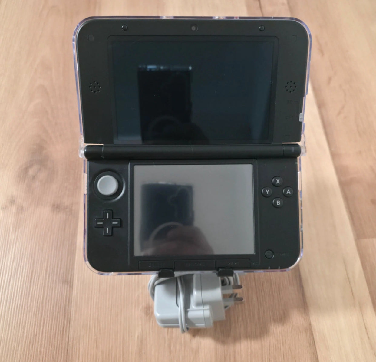 Black Nintendo 3DS gaming console on a wooden surface Modified Nintendo 3DS XL with custom firmware, Luma3DS, homebrew apps, emulators, customizable themes, and enhanced performance features.