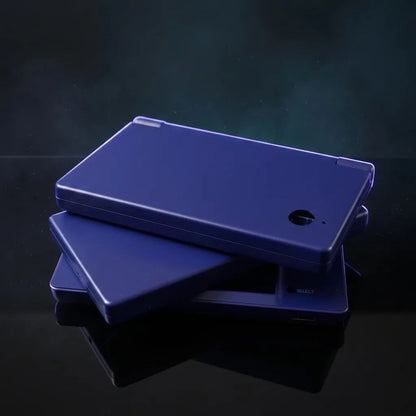 Deep Sea Blue DSi replacement shells stacked on a dark desk, deep indigo housing for a modded Nintendo DSi
