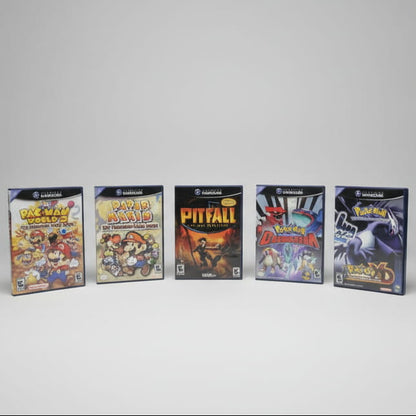 5 Nintendo GameCube game cases displayed in a row including Pac-Man World 2, Paper Mario, Pitfall, Pokémon Colosseum and Pokémon XD