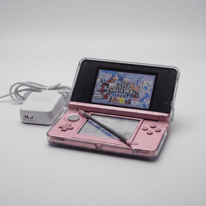Pearl Pink modded Nintendo 3DS with charger displaying Super Smash Bros, preinstalled games UK