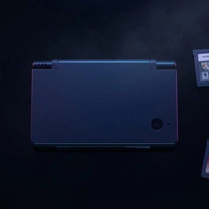 Obsidian Black DSi replacement shell with a cyan edge glow, stealth console on a dark background