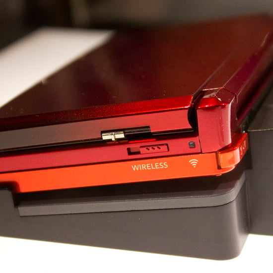 Video showing a modded Nintendo 3DS with 128GB storage running custom firmware, featuring a custom theme interface, Homebrew menu, and various installed emulator apps. Clear plastic case with branding on a blue and wooden surfacePink handheld gaming device with screen displaying 'Super Smash Bros.' game on a glittery gold surface. 3DS Modded 3DS Custom Firmware 128gb emulators, anemone, h shop, homebrew